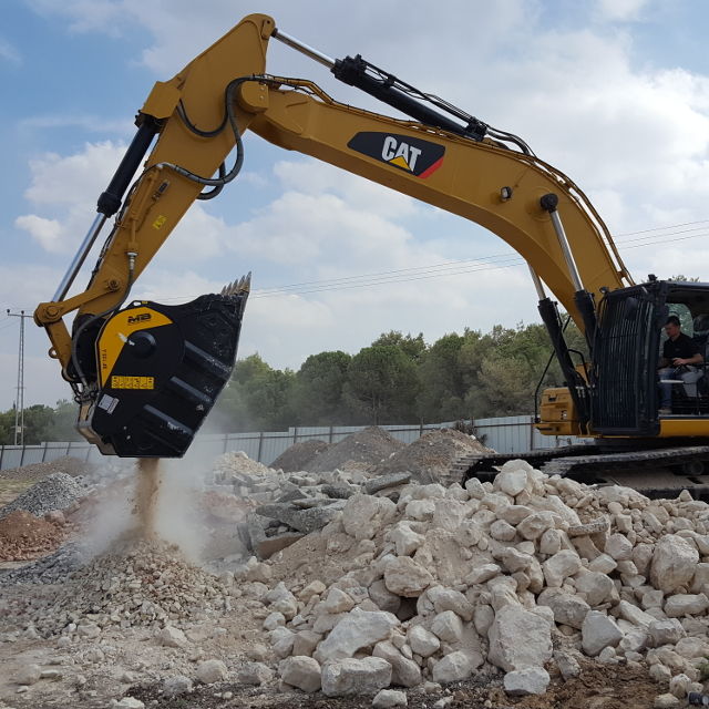 Caterpillar 336F excavator breaking up rocks on a construction site.