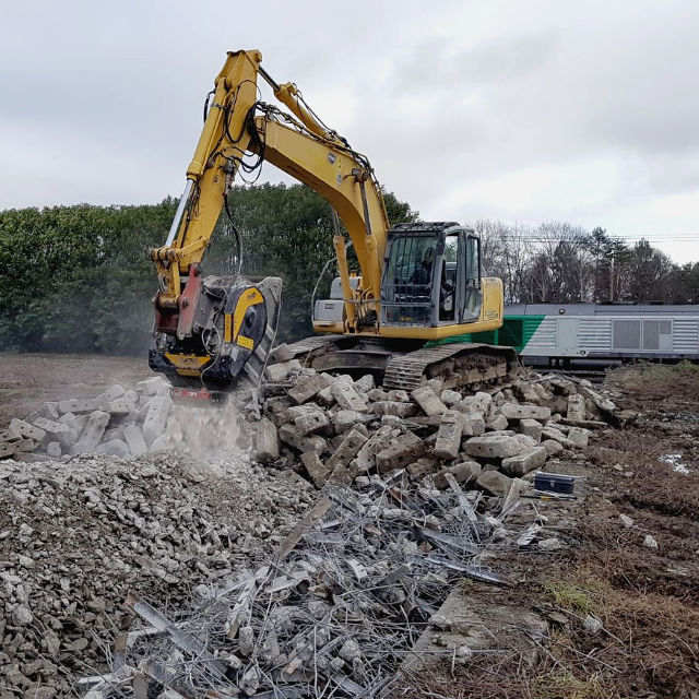 MB Crusher BF80.3 S4 excavator working on a pile of bricks with a cloudy sky in the background