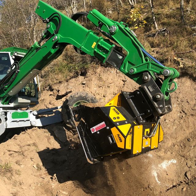 Menzi Muck MB HDS214 excavator attachment on a dirt surface with trees in the background