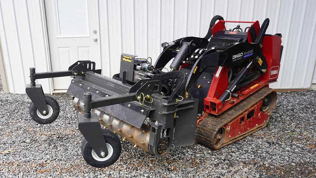 CID Multi-Purpose Power Rake for Mini Skid Steers | Small tracked machine with attachments on a gravel surface