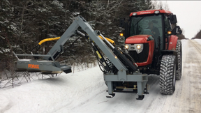 Red tractor with a snow removal attachment on a snowy road