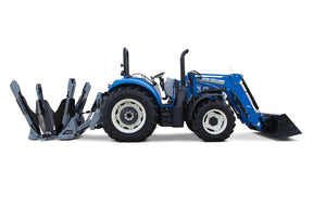 A Baumalight tree spade attachment with four blades and dual-hinged outer frame arms, mounted on a blue tractor with landscaping equipment.