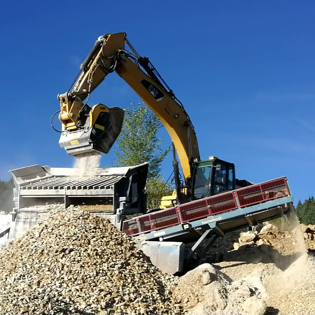 Caterpillar-330 Hydraulic excavator loading rocks into a truck against a blue sky.