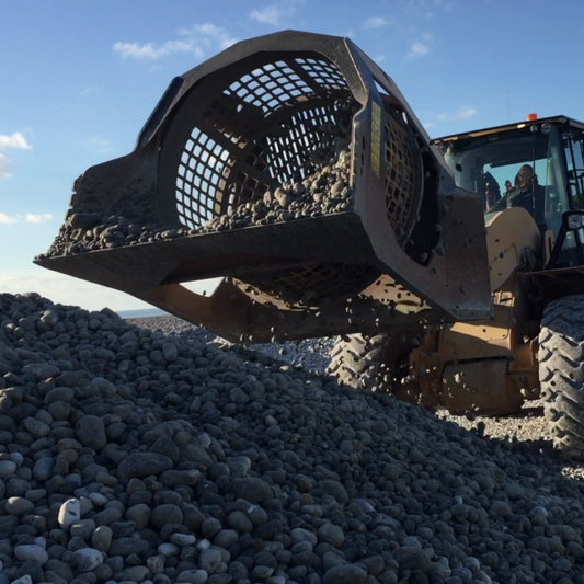 Caterpillar-962M truck with a large bucket filled with rocks against a blue sky.