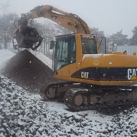 Caterpillar 312C excavator clearing snow in a snowy landscape