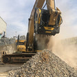 Caterpillar 336 Hydraulic Excavator working on a pile of gravel with a building in the background