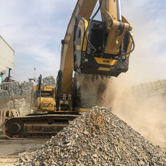 Caterpillar 336 Hydraulic Excavator working on a pile of gravel with a building in the background