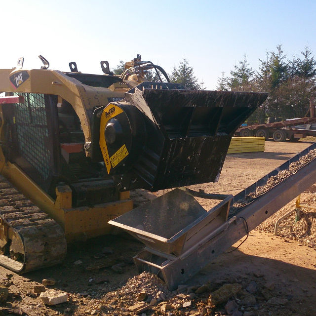 Caterpillar MB-L140 bulldozer on a construction site with trees in the background
