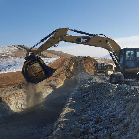 Caterpillar MB-S18 excavator at a construction site with mountains in the background
