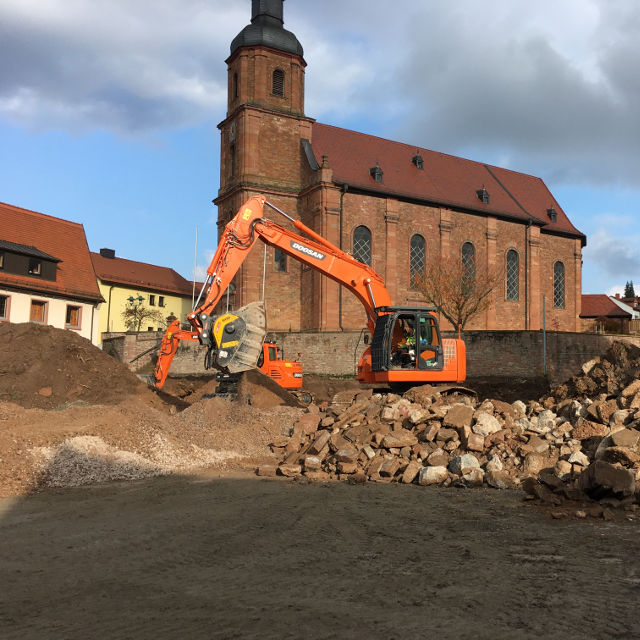 Doosan MB-BF90 S4 Excavator working on a construction site with a church in the background