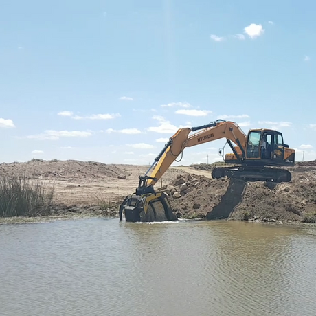 Hyundai MB-S18 Excavator digging near a body of water with a clear sky in the background