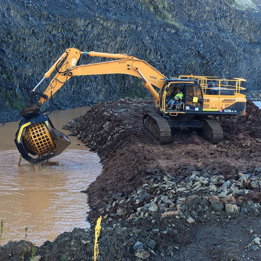 Hyundai MB S23 excavator at a construction site with water and rocks in the background