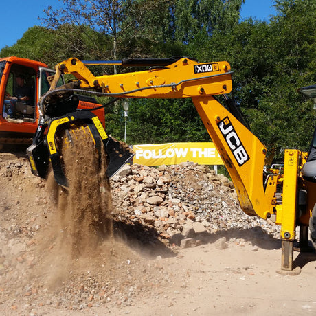 JCB 3CX excavator at a construction site with trees in the background