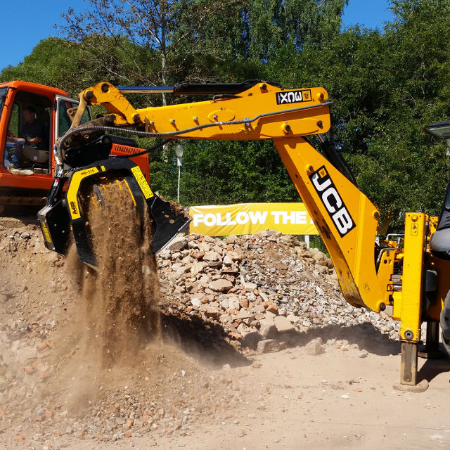 JCB 3CX excavator at a construction site with trees in the background