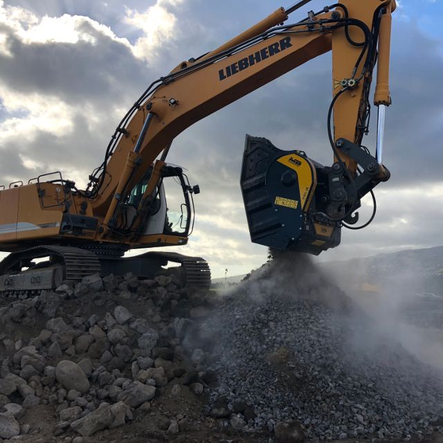 Liebherr-944 excavator operating on a construction site with a cloudy sky.