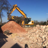 Liebherr MB-L200 excavator working on a construction site with piles of rubble and debris.