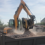 JCB excavator loading gravel into a truck on a clear day.