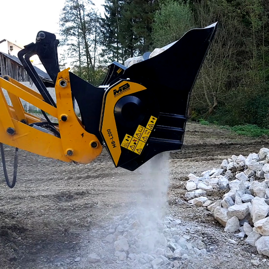 Backhoe attachment clearing a path with rocks and trees in the background