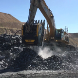 MB - BF150.10 as an attachment operating on a construction site with rocks and clear sky.