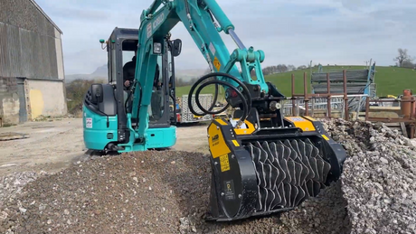 MB Crusher HDS207 Shaft Screener excavator with a large black attachment on a construction site.