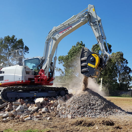 Takeuchi-TB2150 Excavator with a clamshell bucket clearing rocks on a construction site.