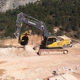 Volvo BF135.8 excavator at a construction site with trees in the background