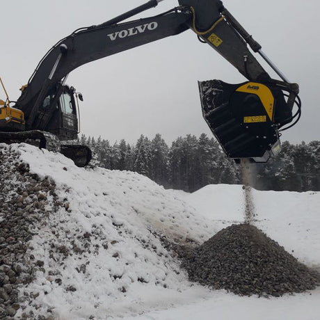 Volvo BF90.3 excavator operating in a snowy landscape with trees in the background