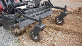 CID Multi-Purpose Power Rake for Mini Skid Steers | Close-up of a lawn mower attachment on a gravel surface