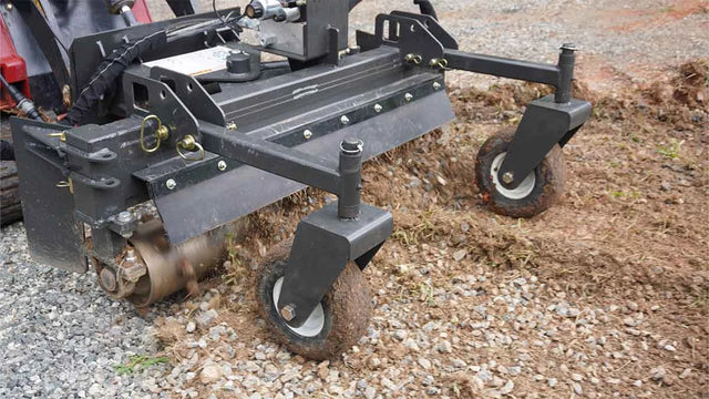 CID Multi-Purpose Power Rake for Mini Skid Steers | Close-up of a lawn mower attachment on a gravel surface
